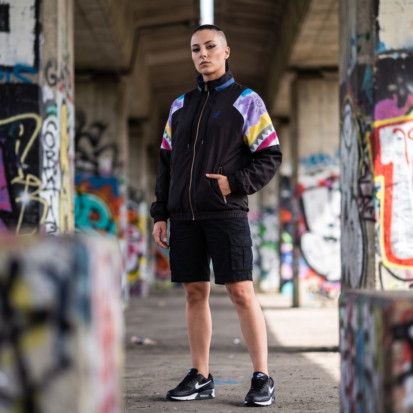 Modella indossa giacca GABBERPLANET Australian Native Old Track Jacket nera con maniche stampate in stile anni 90