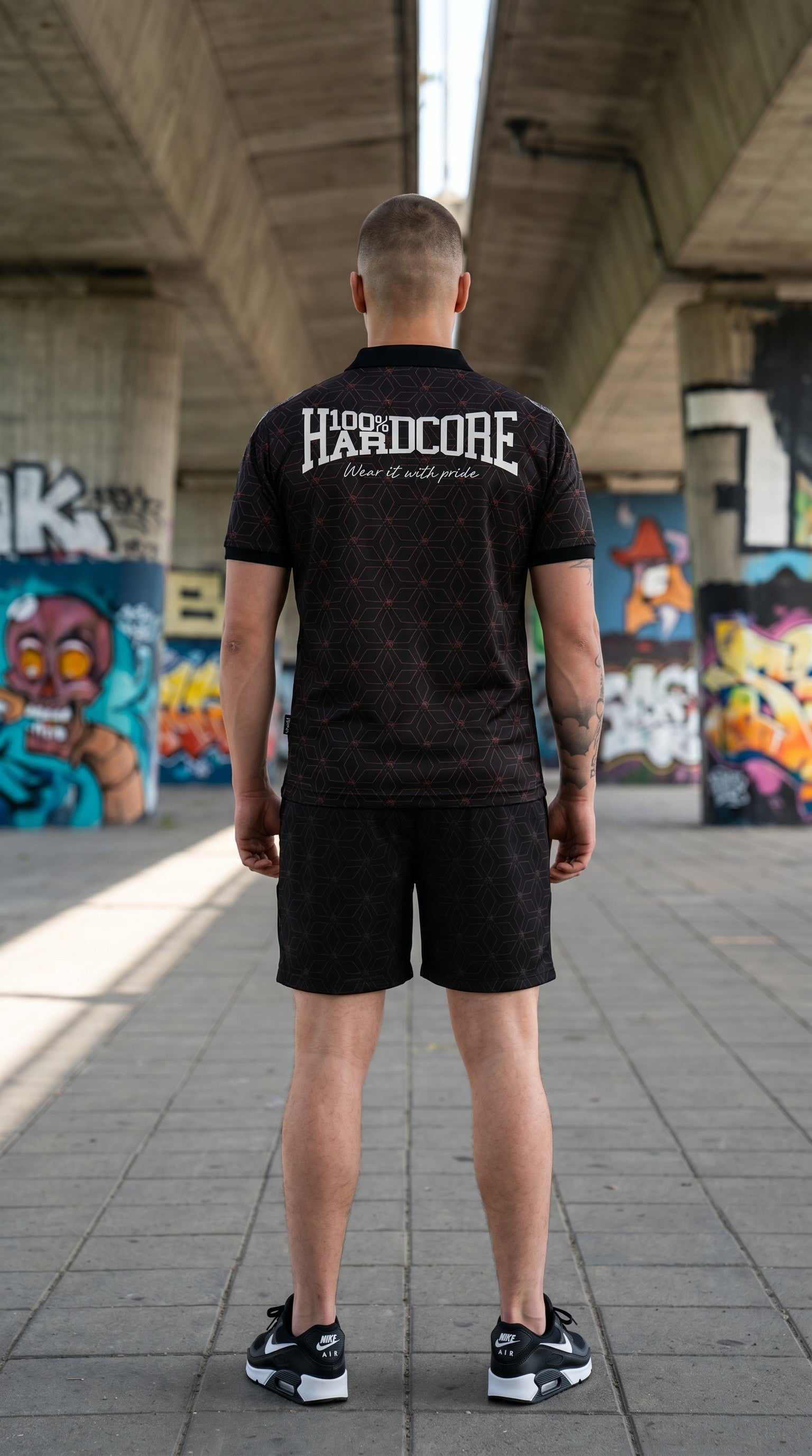 Modello di spalle indossa maglia GABBERPLANET 100% Hardcore rossa e nera con stampa sul retro e pantaloncini abbinati