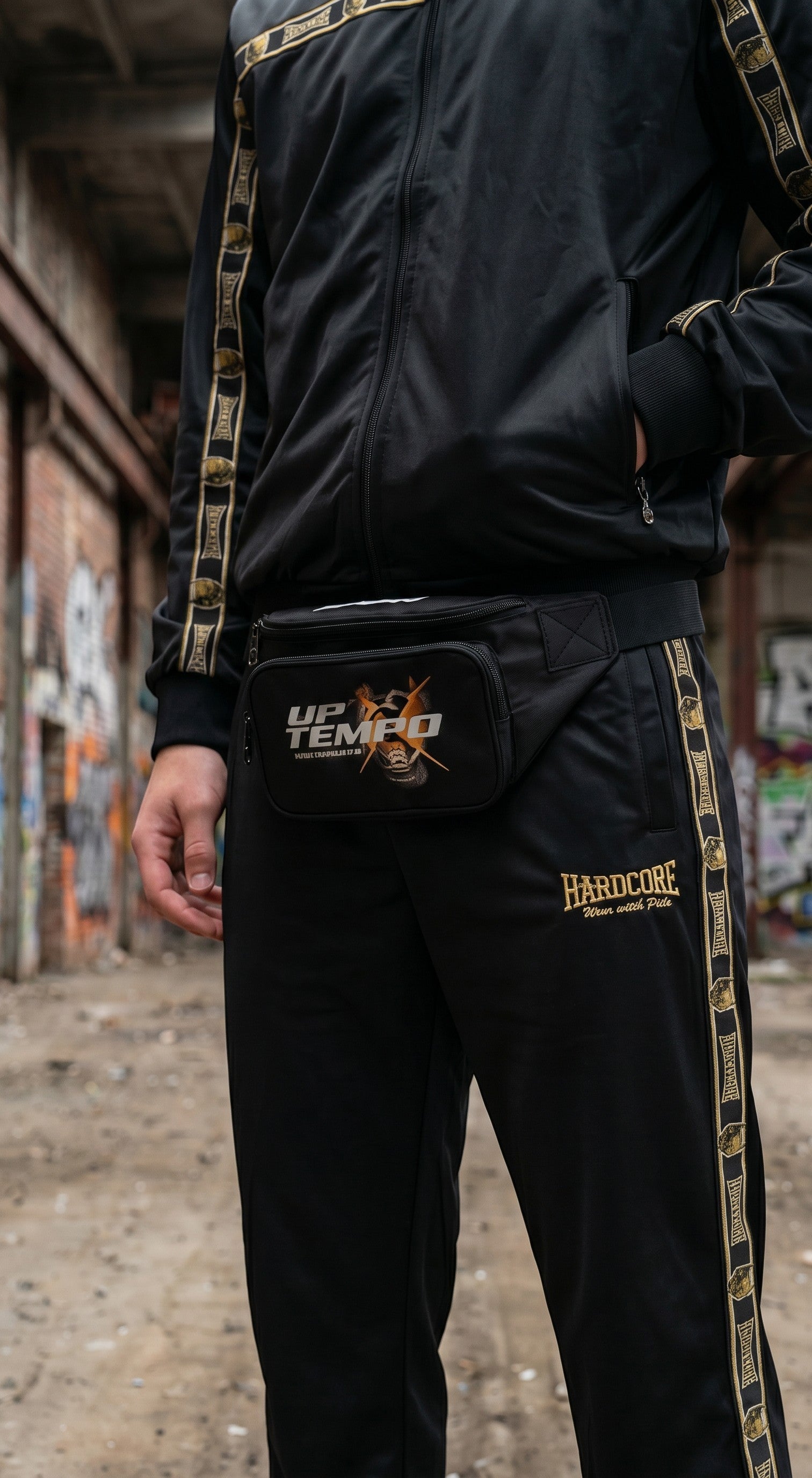 Tuta GABBERPLANET Essential Gold nera in poliestere con dettagli dorati e marsupio, stile hardcore unisex.