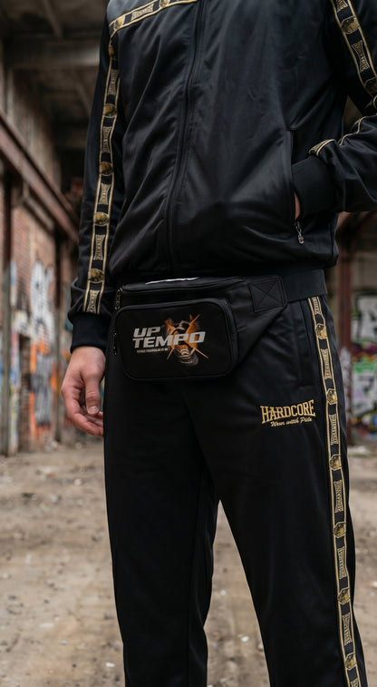Tuta GABBERPLANET Essential Gold nera in poliestere con dettagli dorati e marsupio, stile hardcore unisex.